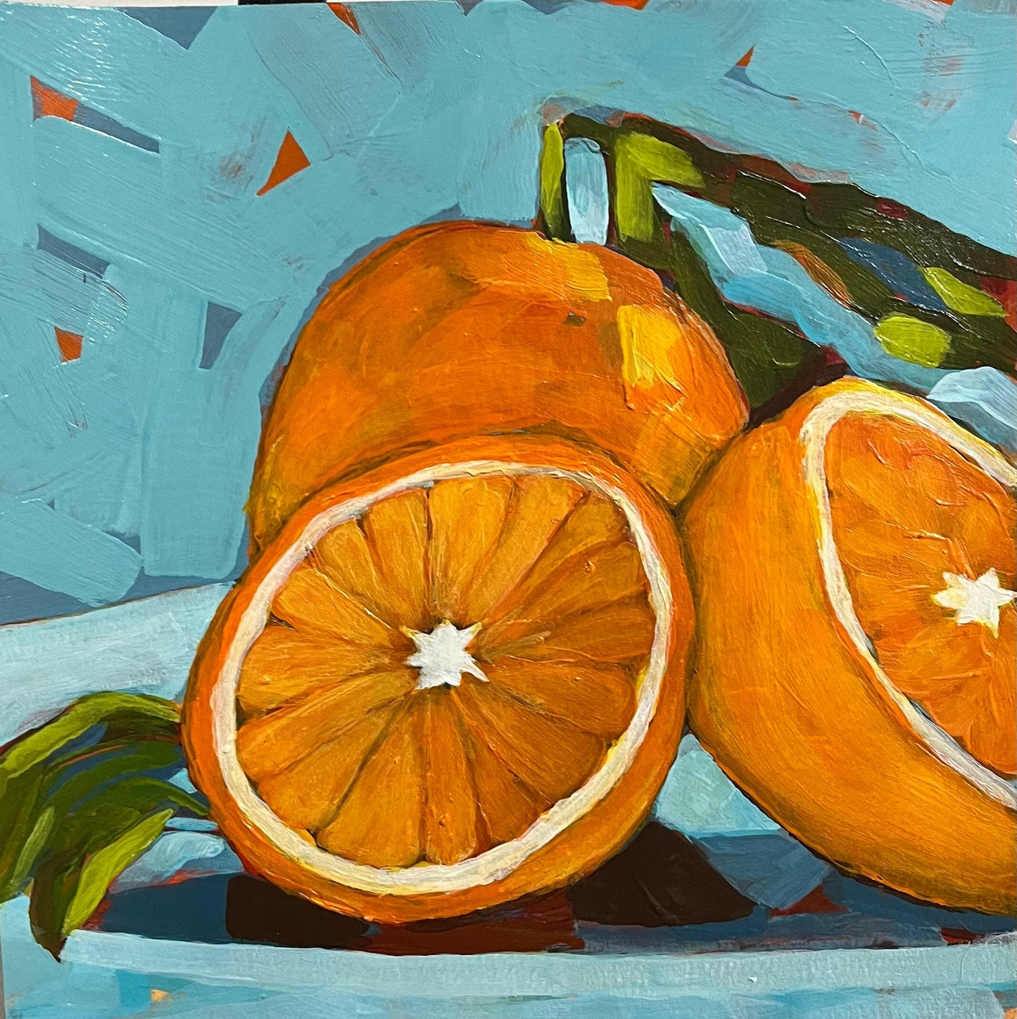 Vibrant still life artwork featuring bright orange citrus fruits, one whole and two halves, on art paper