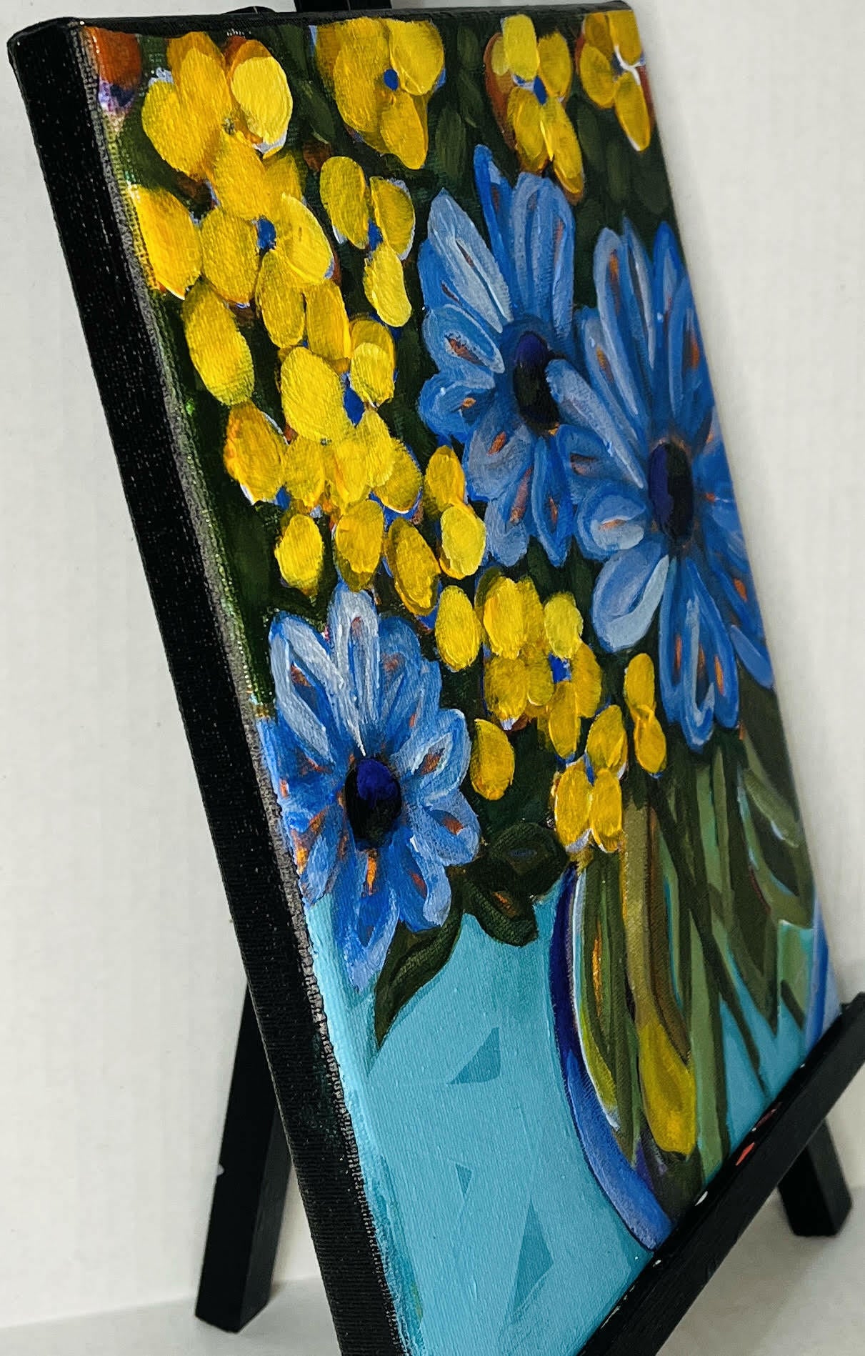 Side View of Blue flower painting depicting a lively bouquet of blue and yellow blossoms in a teal vase, ideal for home decor.